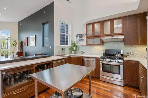 a kitchen with stainless steel appliances a stove a sink cabinets and a window