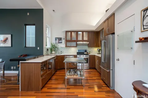 a kitchen with stainless steel appliances granite countertop a stove top oven a refrigerator a dining table and chairs
