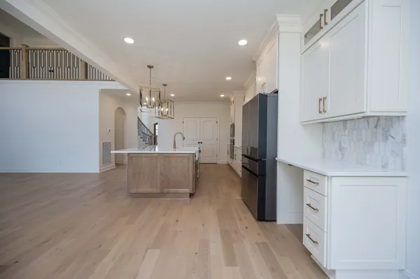 a kitchen with stainless steel appliances granite countertop a refrigerator a sink dishwasher a stove and a dining table with wooden floor