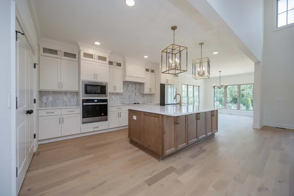 a kitchen with kitchen island a counter top space a sink a refrigerator and a stove