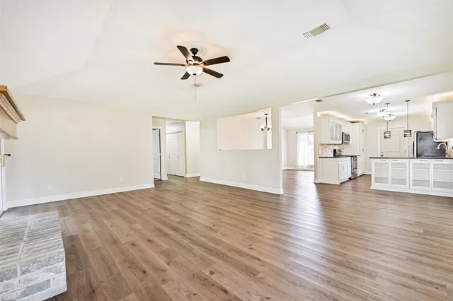 a view of a kitchen and an empty room with wooden floor