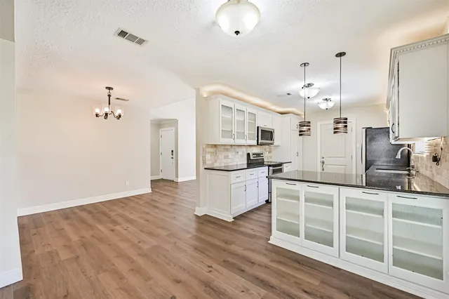 a large kitchen with kitchen island white cabinets and stainless steel appliances