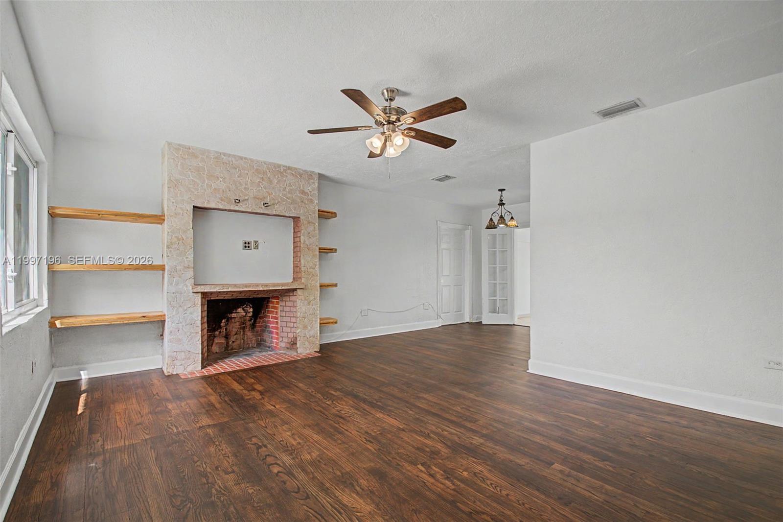 3951 Southwest 2nd Terrace Miami, FL 33134 - Photo 7 of 32 an empty room with a fireplace and a ceiling fan