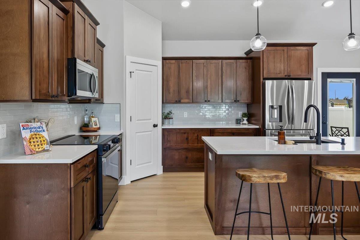 1201 Jade Drive Rupert, ID 83350 - Photo 13 of 27 Kitchen featuring wood cabinetry, white countertops, stainless steel appliances, and a tiled backsplash