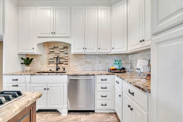 a kitchen with granite countertop a sink stove and cabinets