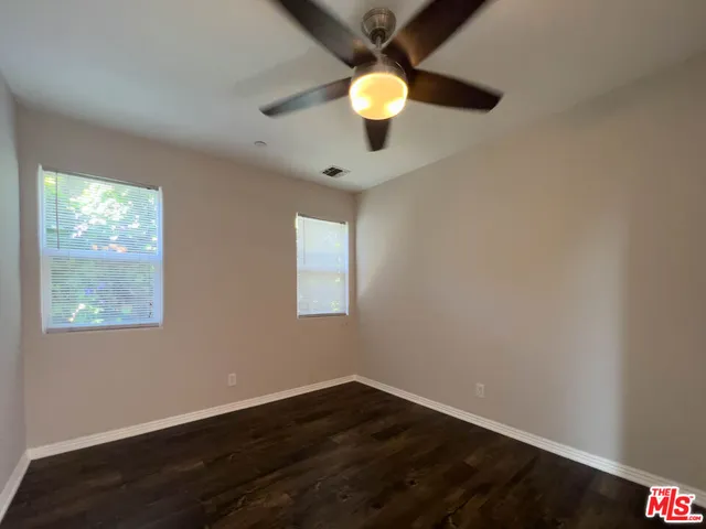 a view of an empty room with wooden floor and window