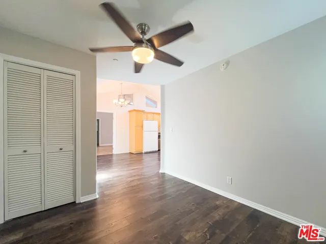 an empty room with wooden floor a ceiling fan and windows