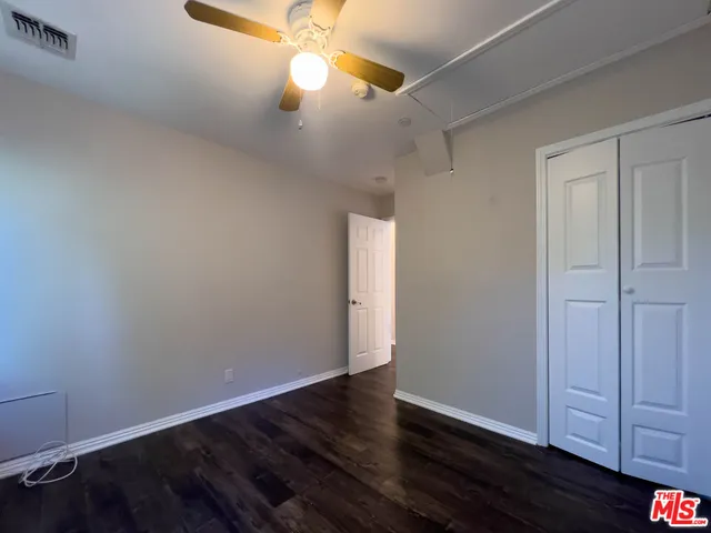 an empty room with wooden floor and fan