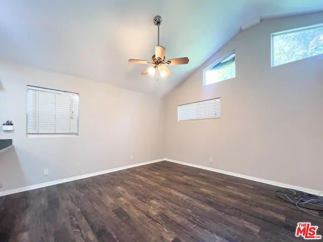 a view of a room with wooden floor chandelier fan and windows