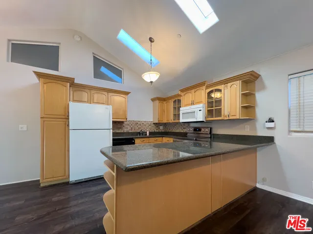 a kitchen with stainless steel appliances granite countertop a sink a refrigerator and a granite counter tops with wooden floors