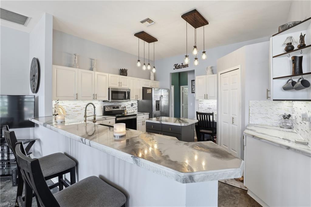 3236 Potomac Court Naples, FL 34120 - Photo 18 of 47 a kitchen with stainless steel appliances granite countertop a sink stove and refrigerator
