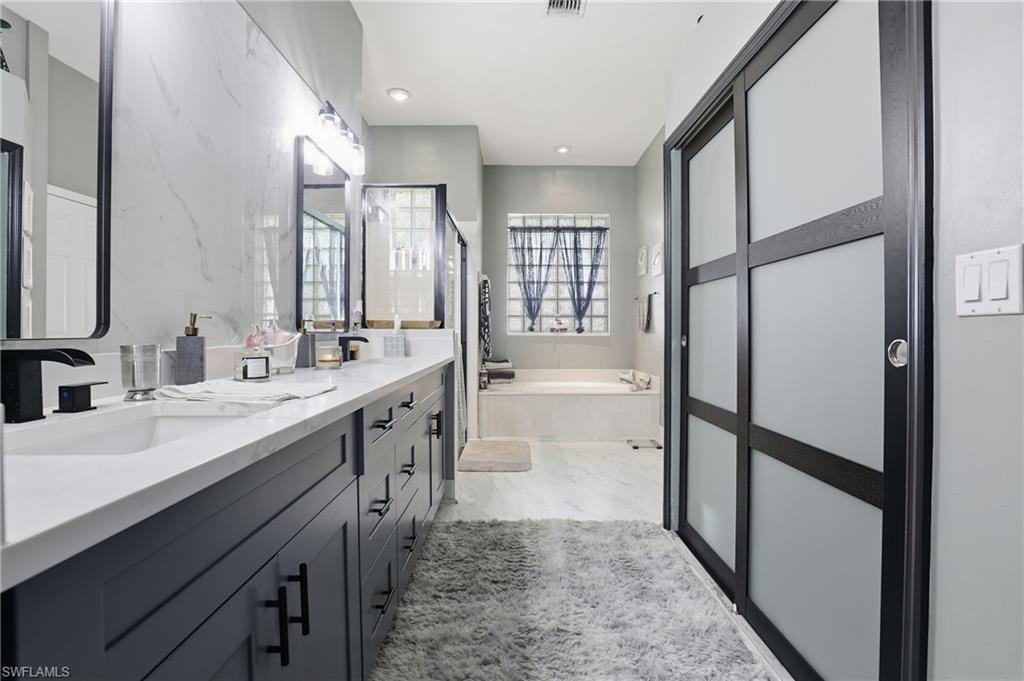 3236 Potomac Court Naples, FL 34120 - Photo 23 of 47 a large bathroom with a double vanity sink a mirror and a bathtub