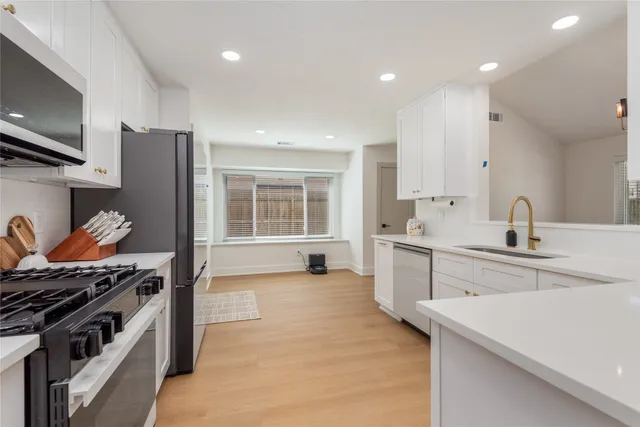 a kitchen with white cabinets sink and stainless steel appliances