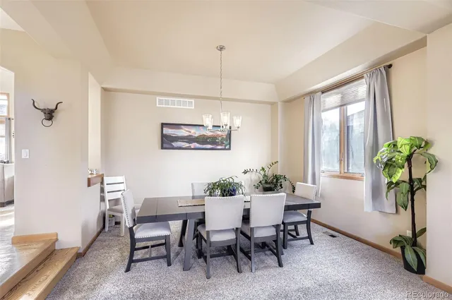a dining room with furniture potted plants and wooden floor