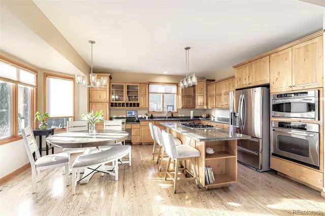 a living room with stainless steel appliances kitchen island granite countertop a table chairs and a refrigerator