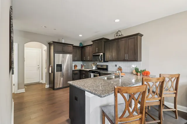 a kitchen with stainless steel appliances granite countertop a refrigerator a stove top oven a sink and dishwasher