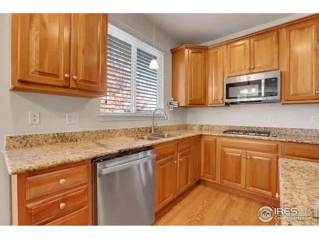 a kitchen with stainless steel appliances granite countertop a sink a stove a microwave cabinets and a window