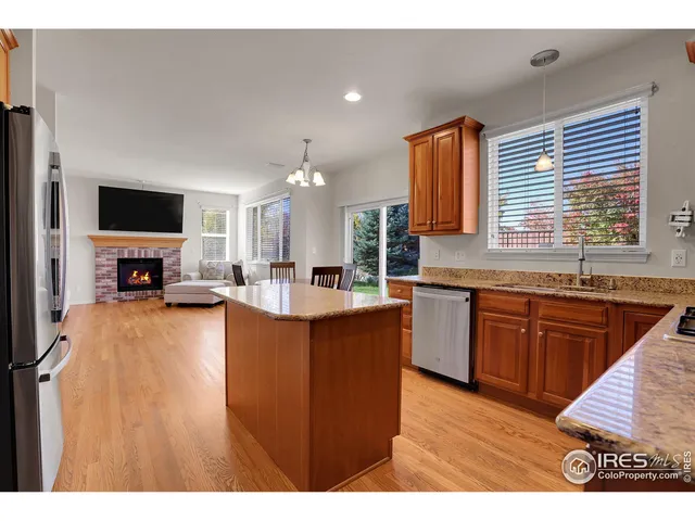 a large kitchen with kitchen island granite countertop wooden cabinets a sink a stove a dining table and chairs