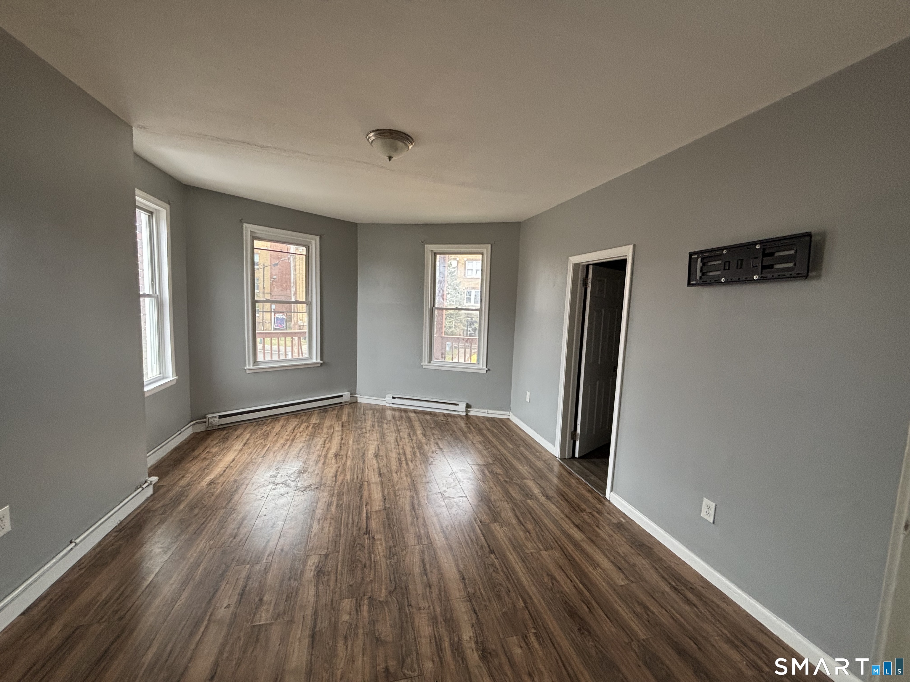 a view of empty room with window and wooden floor