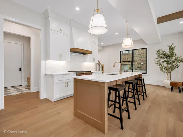 a kitchen with stainless steel appliances kitchen island a table chairs in it and white cabinets