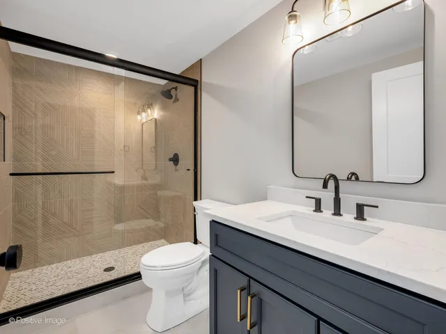 a bathroom with a granite countertop sink toilet a mirror and shower