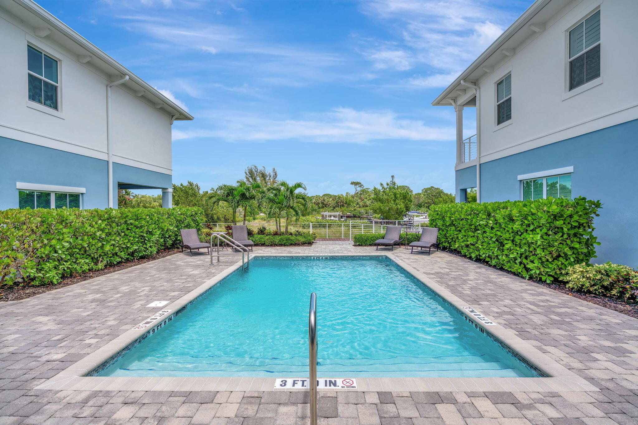 4680 Southeast Manatee Terrace Stuart, FL 34997 - Photo 24 of 34 a view of a patio with plants and a lawn chairs under an umbrella