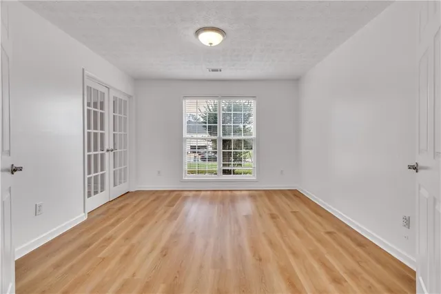 a view of an empty room with wooden floor and a window