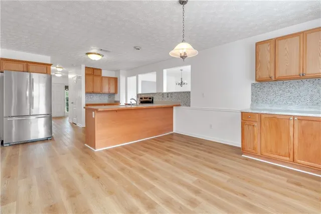 a kitchen with stainless steel appliances granite countertop a refrigerator a sink dishwasher a stove and white countertops with wooden floor