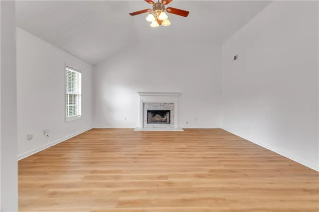 a view of an empty room with window and chandelier fan