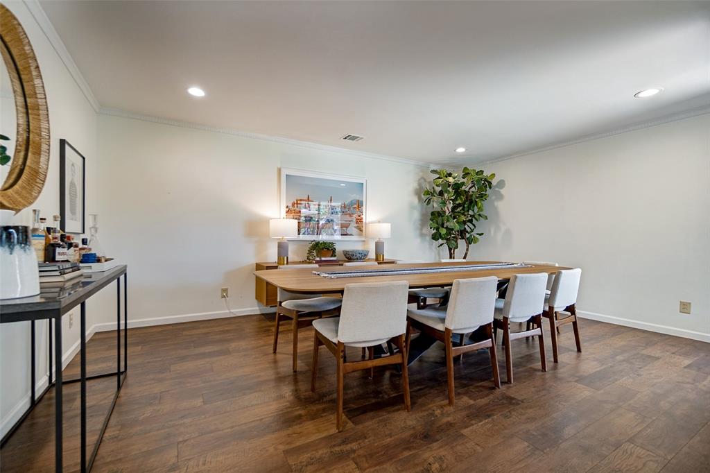 Recessed lighting illuminates the wood-finish flooring and crown molding