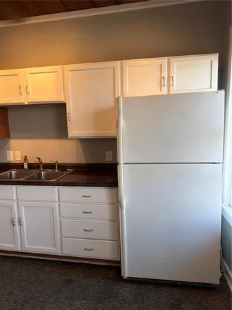 a kitchen with white cabinets and a refrigerator