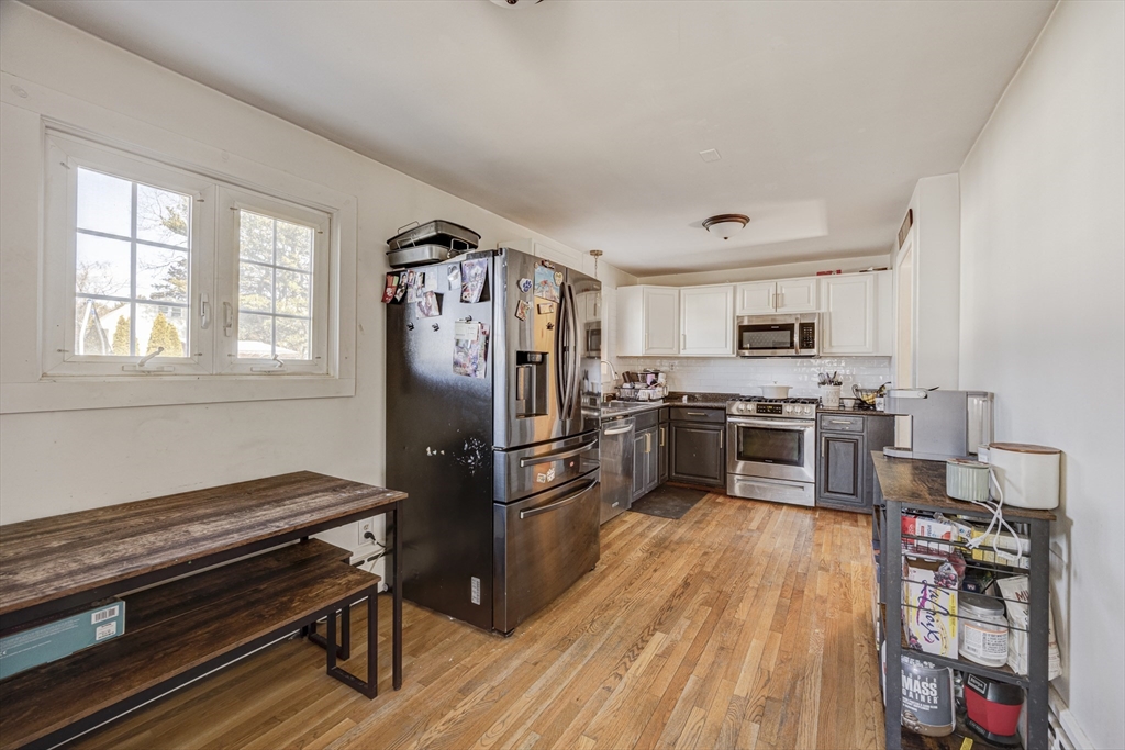 707 Hathaway Road New Bedford, MA 02740 - Photo 8 of 33 a kitchen with a refrigerator wooden floor and stainless steel appliances