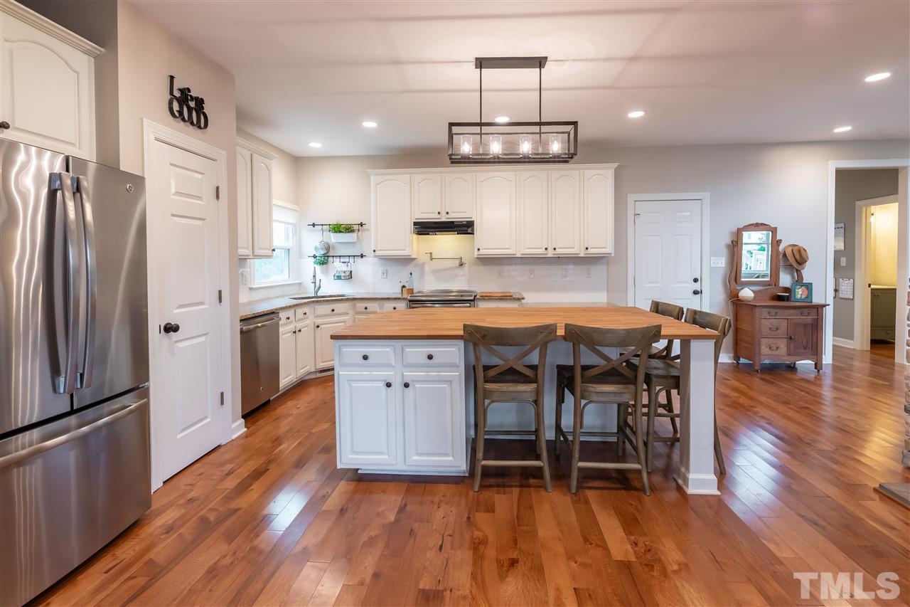 8901 Breeland Way Raleigh, NC 27613 - Photo 5 of 24 a kitchen with stainless steel appliances a dining table chairs refrigerator and microwave