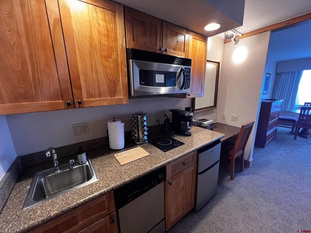 a kitchen with a sink dishwasher a stove and a microwave oven with cabinets