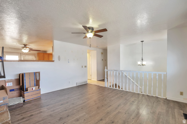 1057 North 700 West Clinton, UT 84015 - Photo 3 of 15 Unfurnished living room featuring ceiling fan, a textured ceiling, wood finished floors, and suspended lighting
