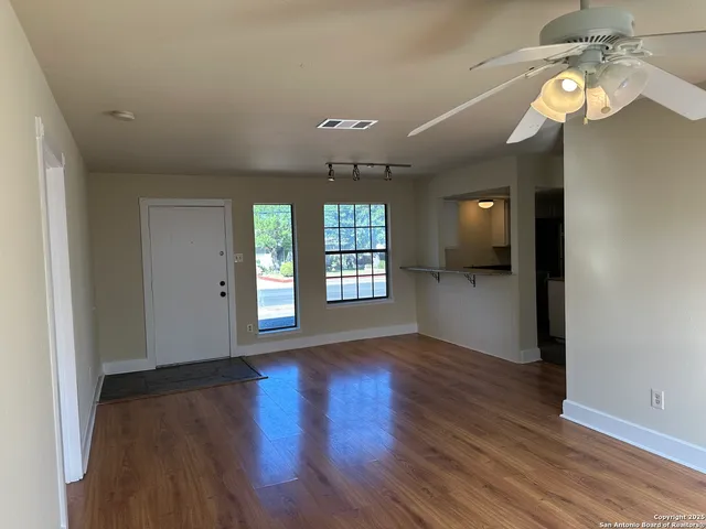 a view of an empty room with window and wooden floor