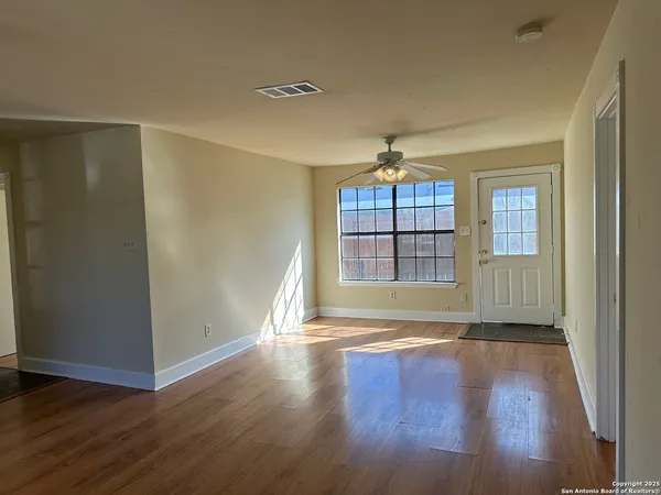 a view of empty room with wooden floor and fan