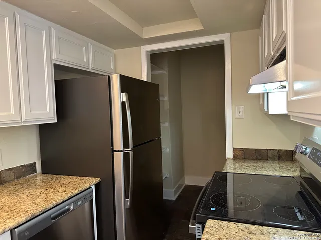 a kitchen with stainless steel appliances granite countertop a refrigerator and a stove