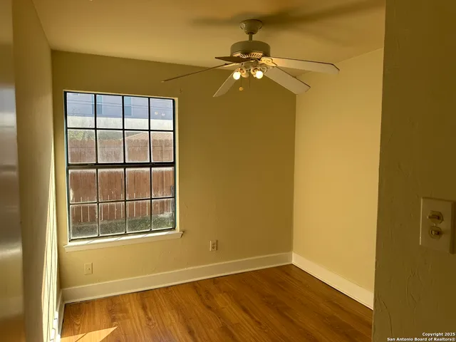 an empty room with windows and chandelier fan