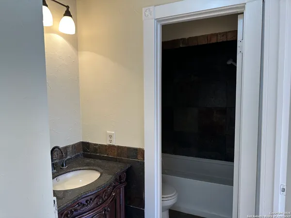 a bathroom with a granite countertop sink and a bathtub