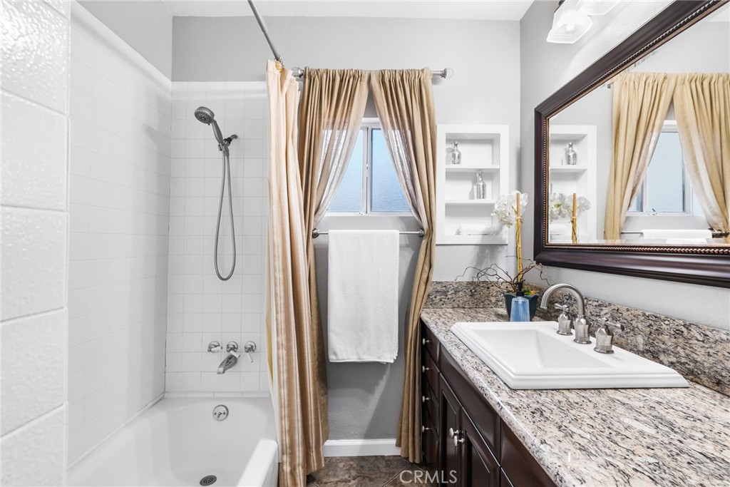 4651 Emerson Street Riverside, CA 92506 - Photo 16 of 30 a bathroom with a granite countertop sink a mirror and a bathtub
