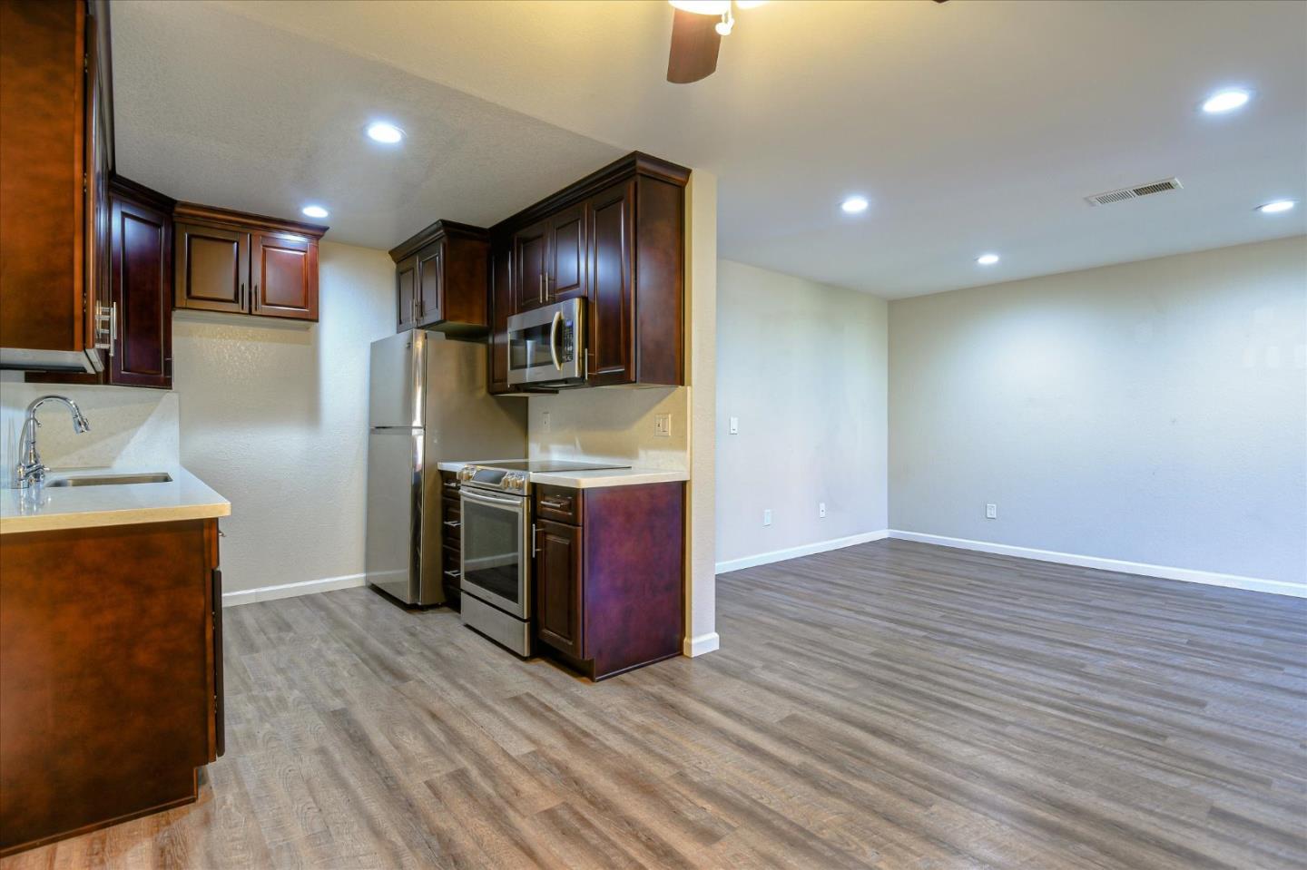 46948 Shale Common, Unit 112 Fremont, CA 94539 - Photo 7 of 30 a kitchen with stainless steel appliances granite countertop a sink a stove top oven a refrigerator with wooden floors