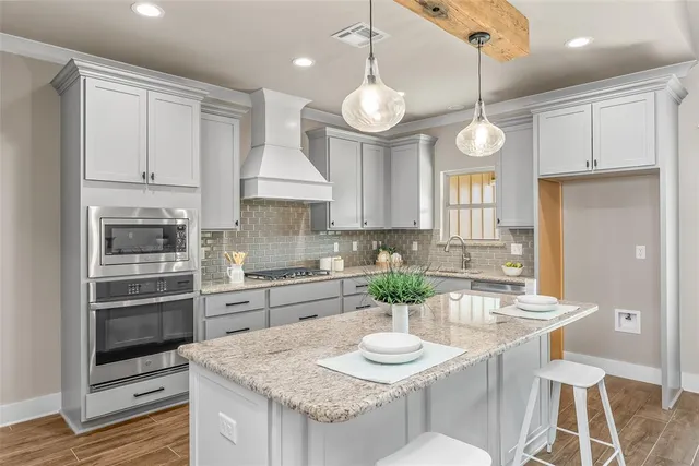 a kitchen with granite countertop a sink cabinets and stainless steel appliances