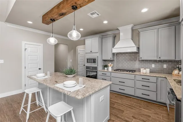 a kitchen with granite countertop a stove a sink a dining table and chairs with wooden floor