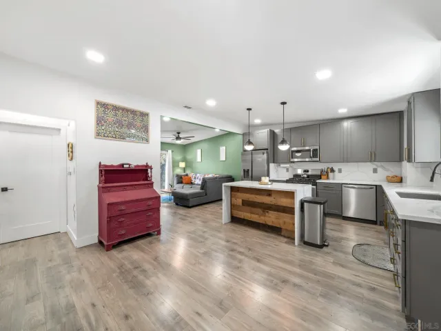 a living room with furniture kitchen view and a wooden floor