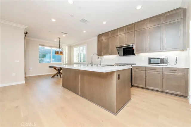 a large white kitchen with a sink a window and stainless steel appliances