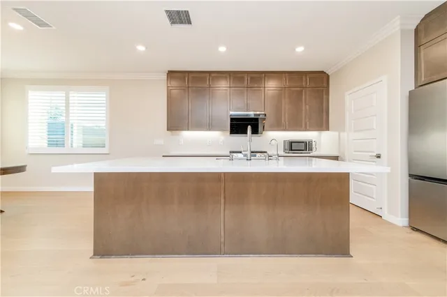 a living room with stainless steel appliances kitchen island granite countertop a couch and a large window