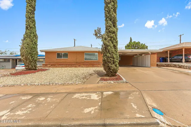 a front view of a house with a yard and potted plants
