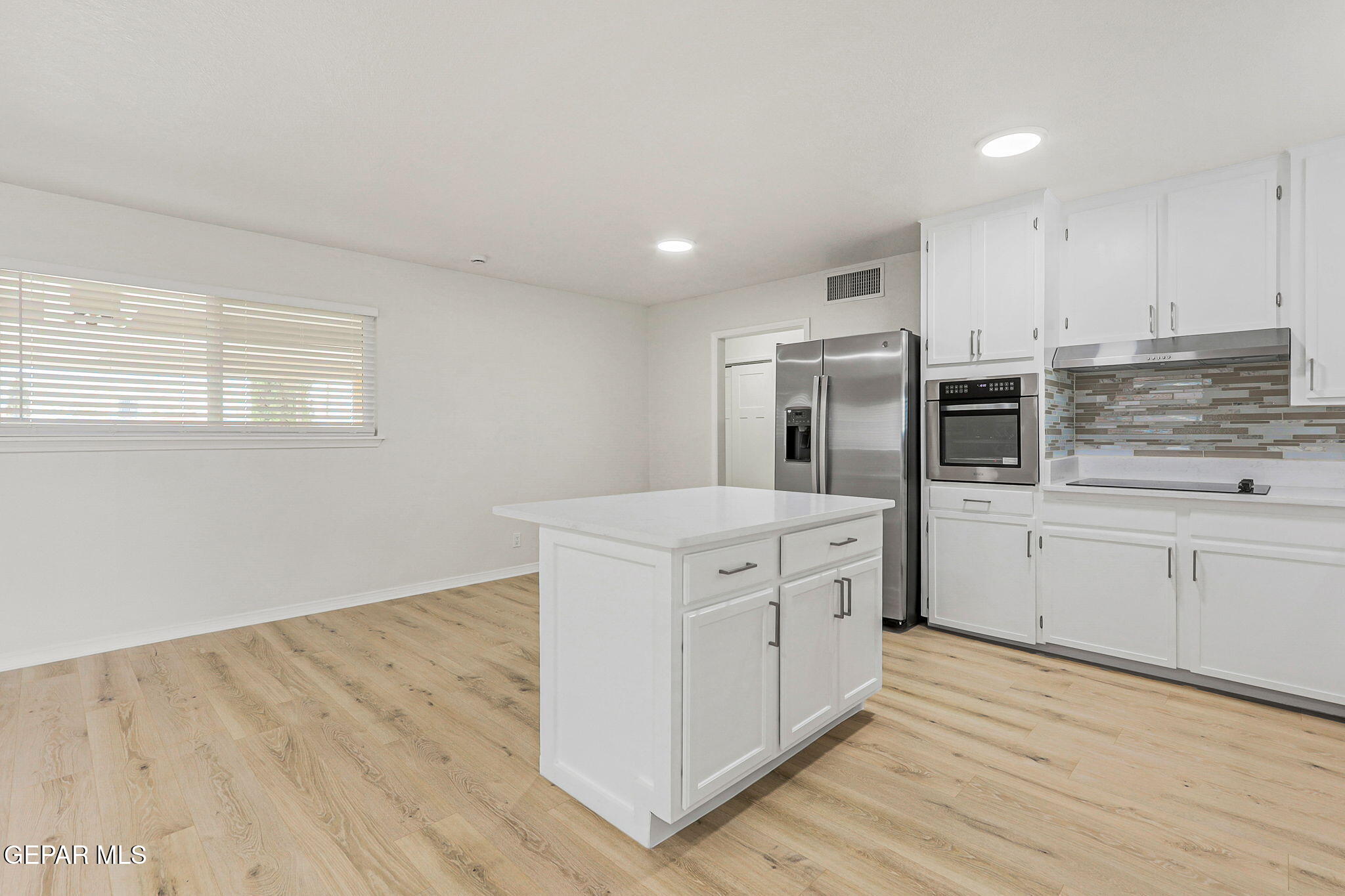 309 Clairemont Road El Paso, TX 79912 - Photo 7 of 40 a kitchen with stainless steel appliances granite countertop a stove a sink and white cabinets with wooden floor