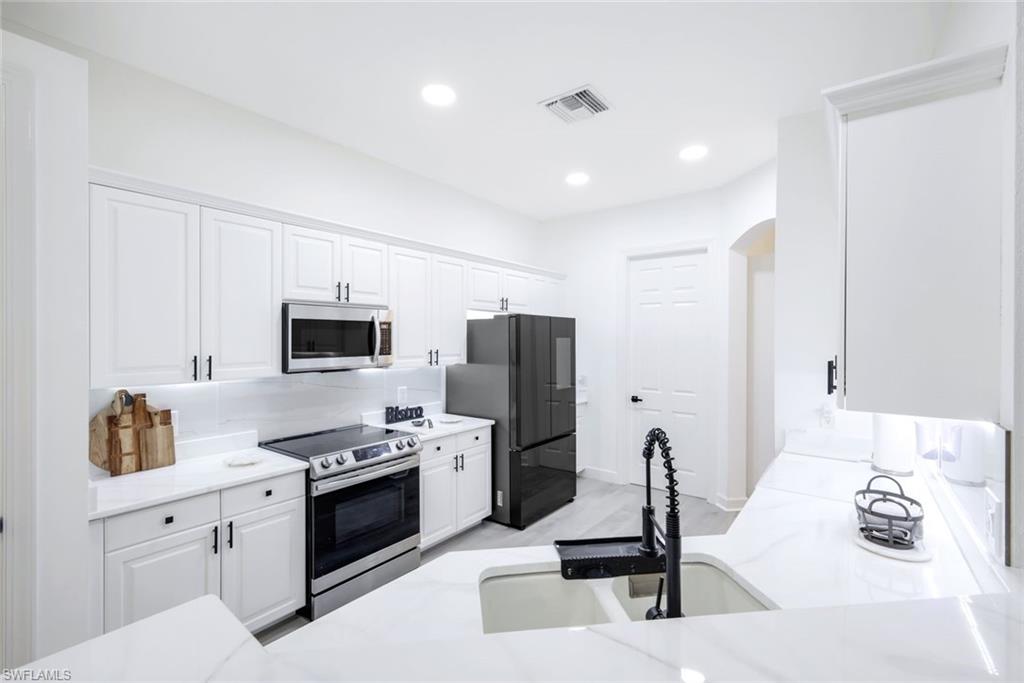16188 Parque Lane Naples, FL 34110 - Photo 11 of 29 a kitchen with stainless steel appliances kitchen island sink refrigerator and stove